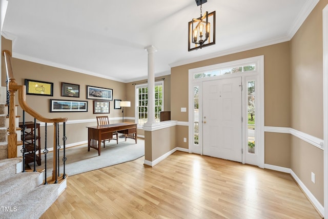 foyer entrance featuring ornamental molding, stairway, light wood finished floors, decorative columns, and baseboards