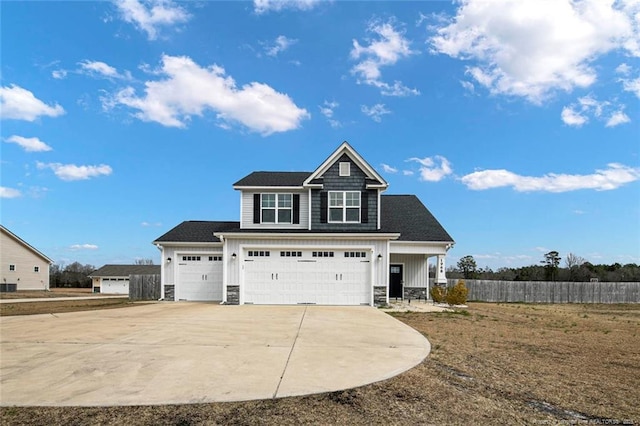 view of front of home featuring stone siding, fence, board and batten siding, and concrete driveway