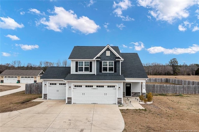 view of front of home with board and batten siding, stone siding, a shingled roof, and concrete driveway