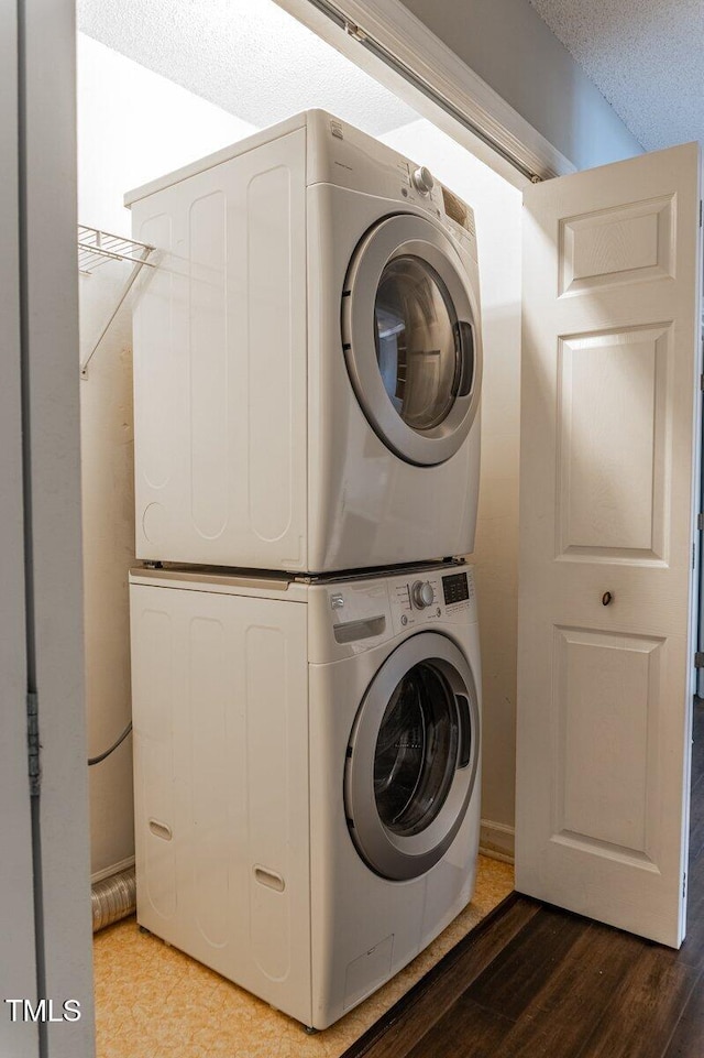 laundry area with stacked washer / drying machine, laundry area, and wood finished floors