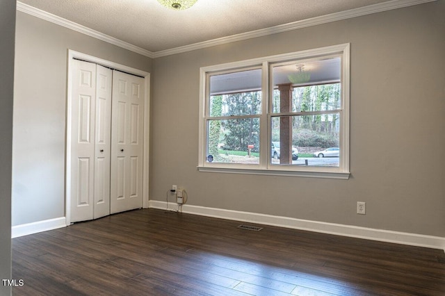 unfurnished bedroom featuring baseboards, visible vents, dark wood finished floors, ornamental molding, and a textured ceiling