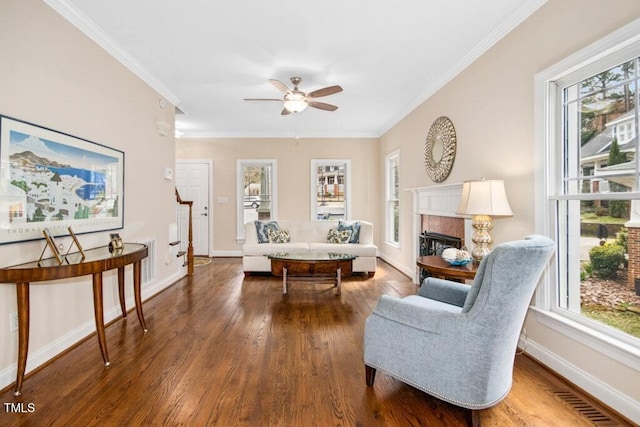 living area featuring wood finished floors, visible vents, baseboards, a fireplace, and ornamental molding