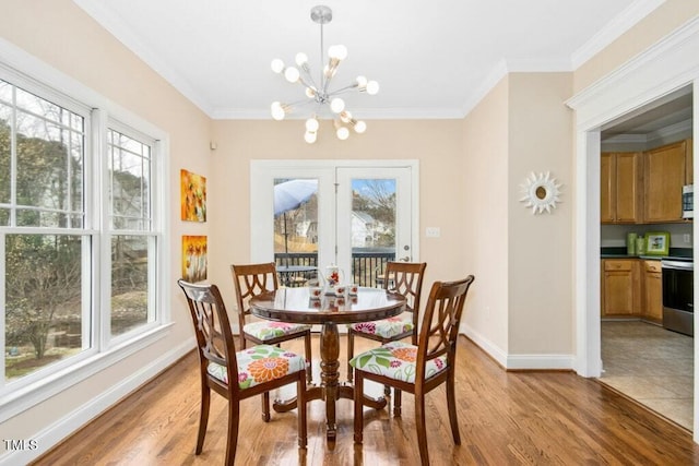 dining room with light wood-style flooring, a notable chandelier, baseboards, and ornamental molding