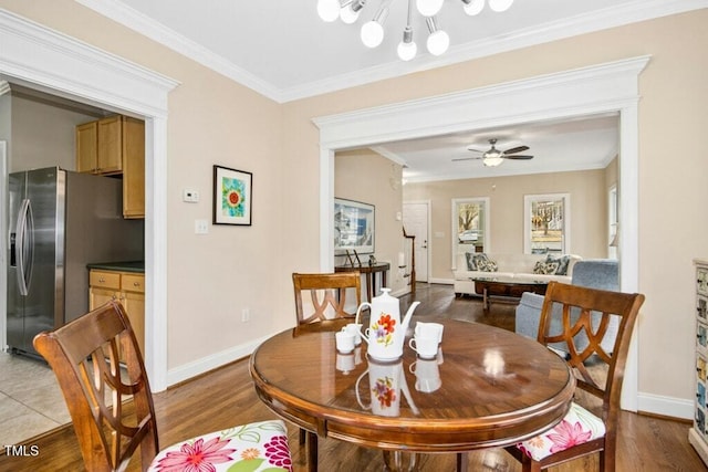 dining room featuring ceiling fan with notable chandelier, crown molding, baseboards, and wood finished floors