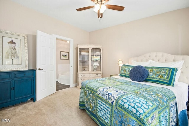 bedroom featuring light colored carpet, ensuite bathroom, and a ceiling fan