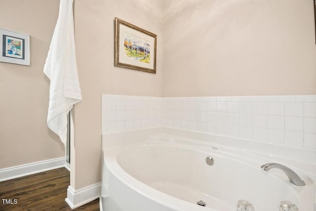 full bathroom featuring baseboards, a garden tub, and wood finished floors