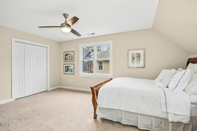 carpeted bedroom featuring visible vents, lofted ceiling, a closet, baseboards, and ceiling fan