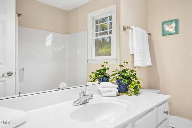 full bathroom with toilet, vanity, and a shower