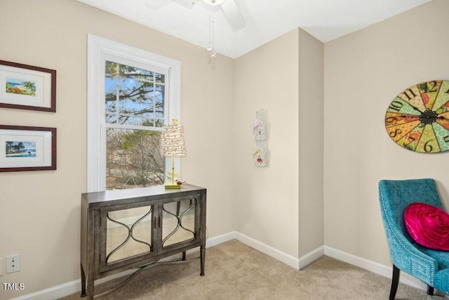 living area with a ceiling fan, baseboards, and carpet floors