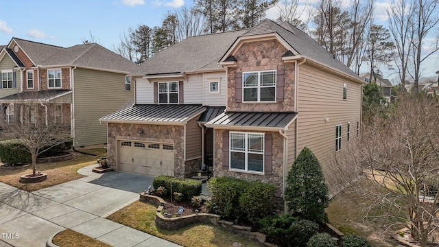 view of front of property with metal roof, stone siding, an attached garage, and a standing seam roof