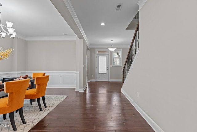 foyer with stairs, an inviting chandelier, wood finished floors, and ornamental molding