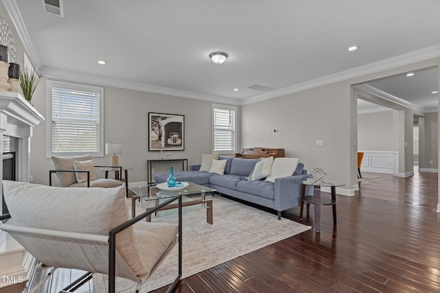 living room with dark wood-type flooring, a fireplace, visible vents, and ornamental molding