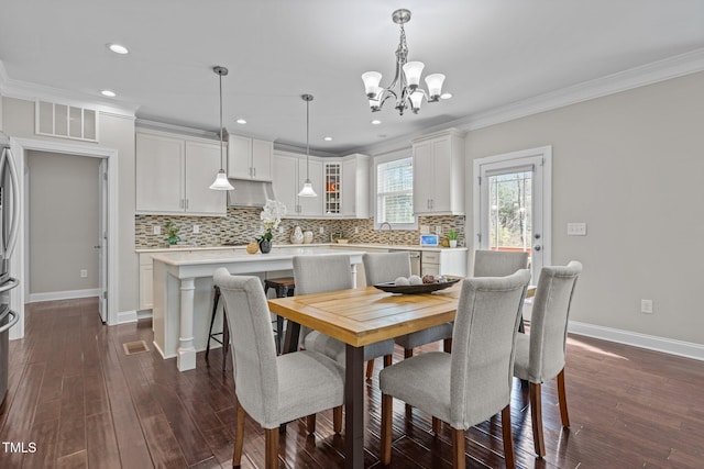 dining space with baseboards, visible vents, dark wood-type flooring, crown molding, and a chandelier