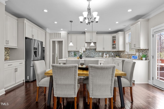 kitchen featuring visible vents, under cabinet range hood, light countertops, an inviting chandelier, and stainless steel fridge