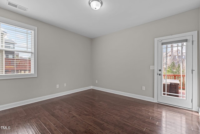 unfurnished room featuring dark wood-type flooring, baseboards, and visible vents