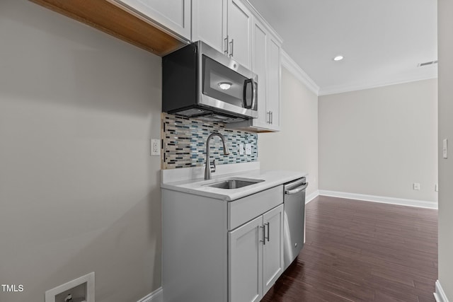 kitchen featuring baseboards, dark wood finished floors, decorative backsplash, appliances with stainless steel finishes, and a sink