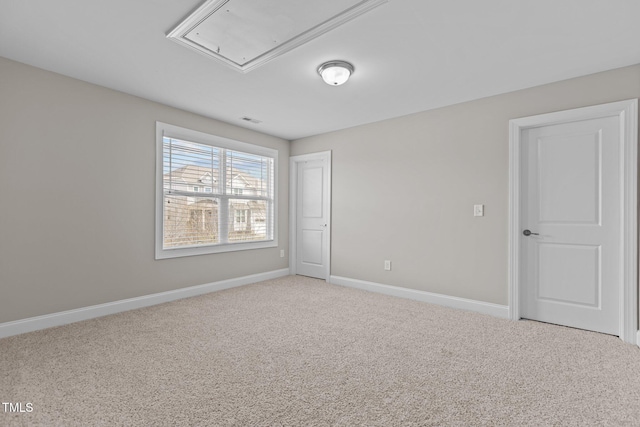 carpeted empty room featuring visible vents, attic access, and baseboards