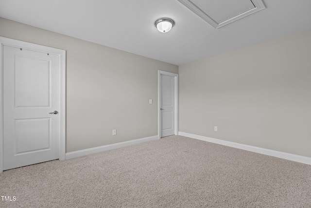 spare room featuring attic access, carpet flooring, and baseboards