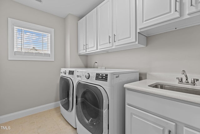 clothes washing area featuring independent washer and dryer, a sink, cabinet space, light tile patterned floors, and baseboards