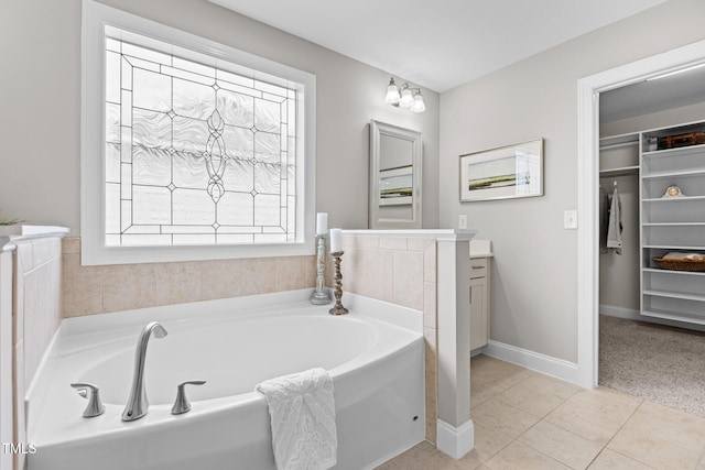 bathroom featuring a garden tub, tile patterned flooring, baseboards, a spacious closet, and vanity