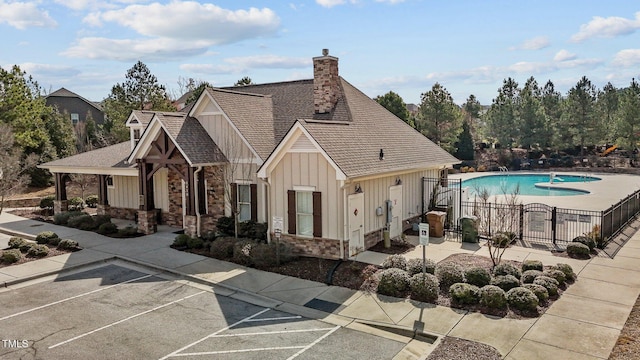 exterior space with a fenced in pool, board and batten siding, fence, a patio area, and stone siding