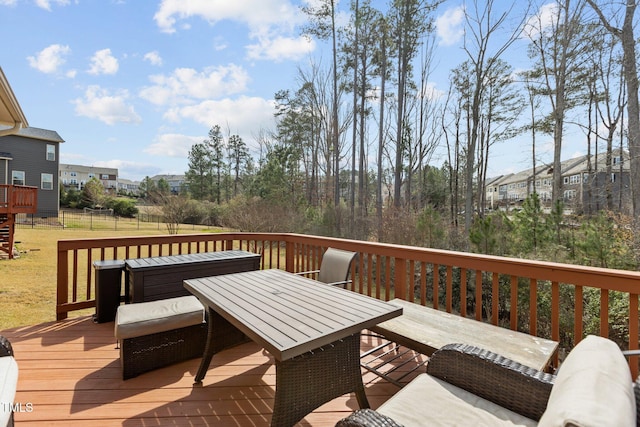 wooden deck featuring outdoor dining space and a lawn