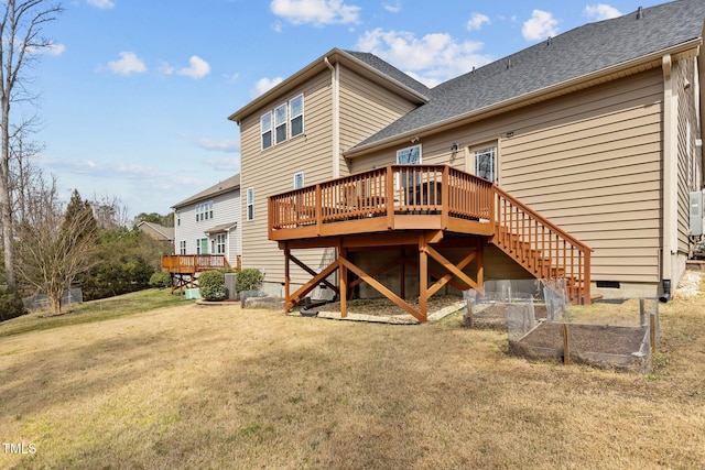 rear view of property with a wooden deck, a lawn, roof with shingles, and stairway