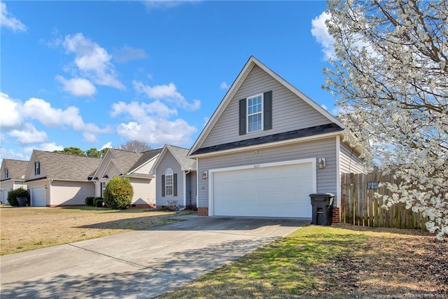 view of front of home featuring driveway, an attached garage, a front yard, and fence