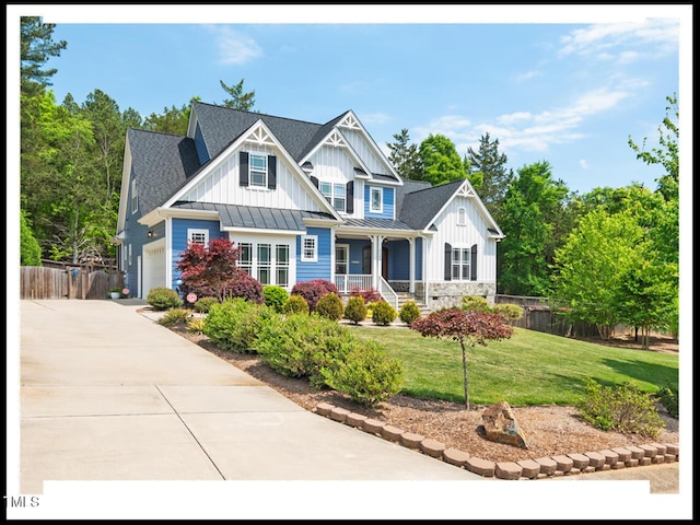 view of front facade with fence, driveway, a standing seam roof, a front lawn, and board and batten siding