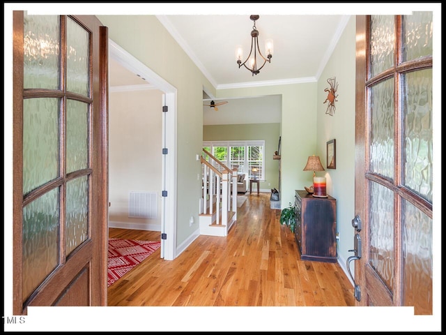 entryway with visible vents, crown molding, light wood finished floors, a chandelier, and stairs