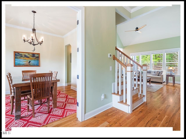 dining space with light wood finished floors, crown molding, baseboards, stairway, and ceiling fan with notable chandelier