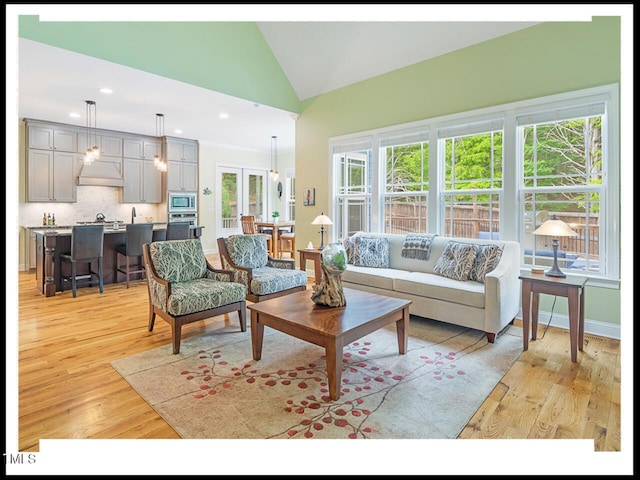 living area featuring recessed lighting, baseboards, lofted ceiling, and light wood finished floors