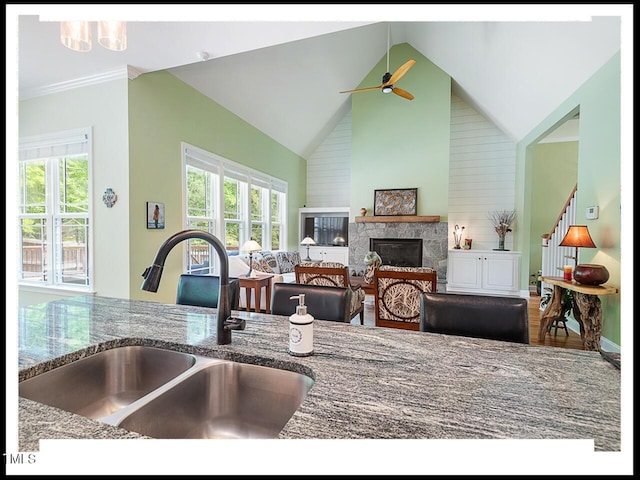 kitchen with plenty of natural light, stone counters, a glass covered fireplace, and a sink