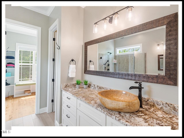 full bath with a healthy amount of sunlight, a walk in shower, vanity, and ornamental molding