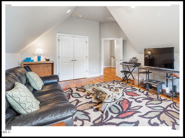 living room featuring baseboards, wood finished floors, and vaulted ceiling