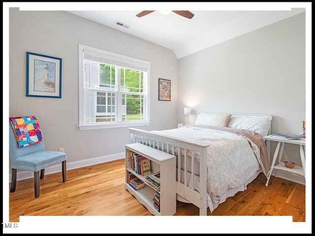 bedroom with visible vents, a ceiling fan, light wood finished floors, baseboards, and vaulted ceiling