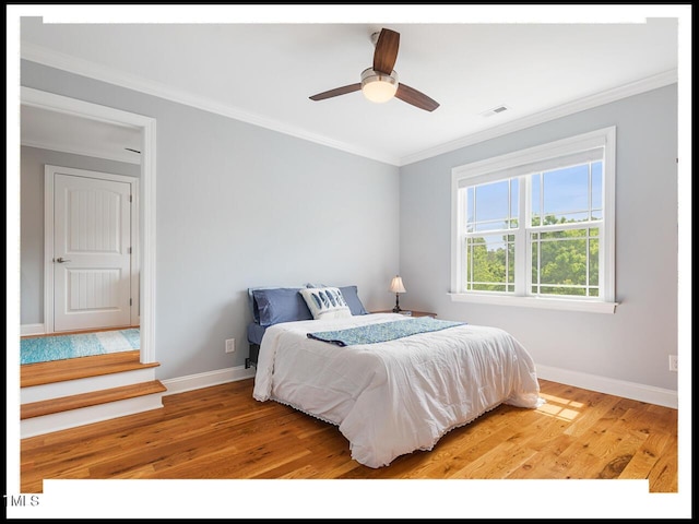 bedroom with visible vents, baseboards, light wood-style floors, and ornamental molding