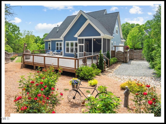 back of property featuring fence, a sunroom, a deck, and a gate