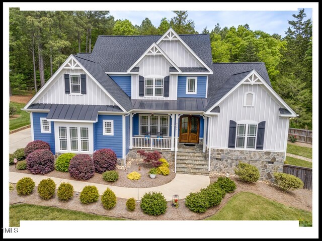 view of front of property featuring covered porch, board and batten siding, a shingled roof, and a standing seam roof