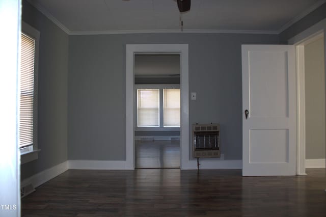 empty room featuring heating unit, crown molding, and wood finished floors