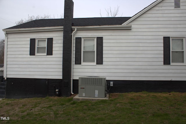 view of property exterior featuring roof with shingles, a lawn, and cooling unit