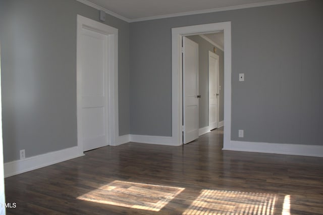 spare room with ornamental molding, dark wood finished floors, and baseboards