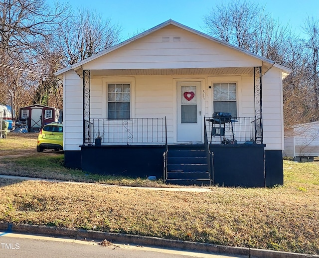 bungalow-style home featuring covered porch and a front lawn