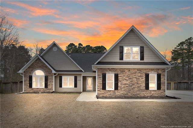 view of front facade with stone siding and fence