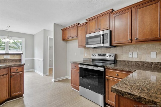 kitchen featuring stainless steel appliances, brown cabinetry, light wood-style flooring, and tasteful backsplash