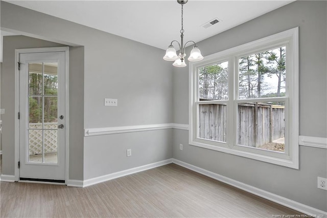 unfurnished dining area featuring visible vents, plenty of natural light, baseboards, and wood finished floors