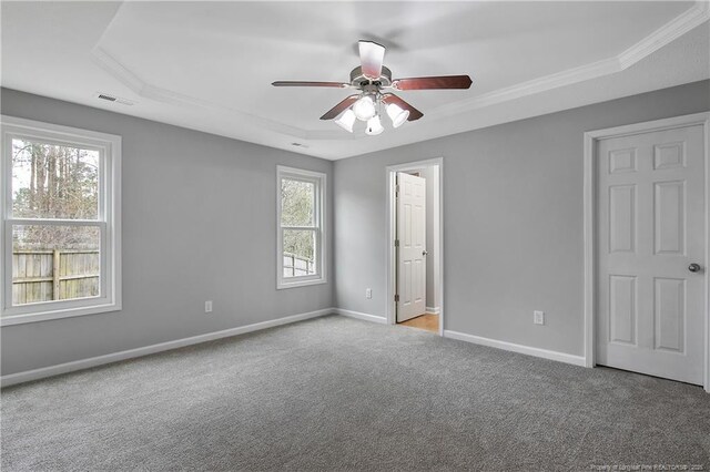 spare room with carpet floors, visible vents, ornamental molding, ceiling fan, and baseboards