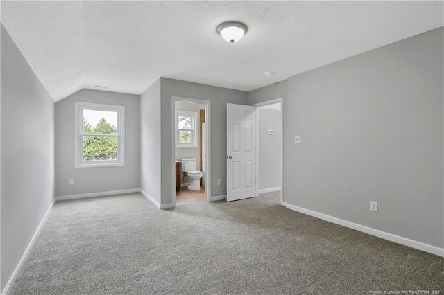 additional living space with carpet floors, vaulted ceiling, a textured ceiling, and baseboards
