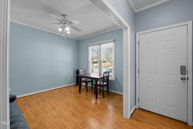 entryway featuring light wood-type flooring, baseboards, a ceiling fan, and crown molding