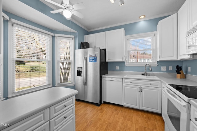 kitchen with light countertops, white cabinets, white appliances, a ceiling fan, and a sink